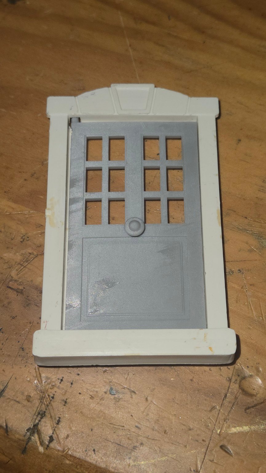 Porte grise reproduite en résine, installée dans un cadre blanc.