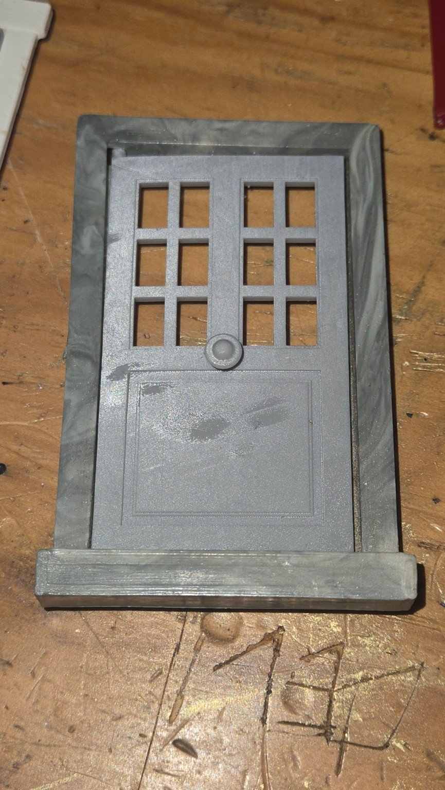 Porte grise reproduite en résine, installée dans un cadre sombre.