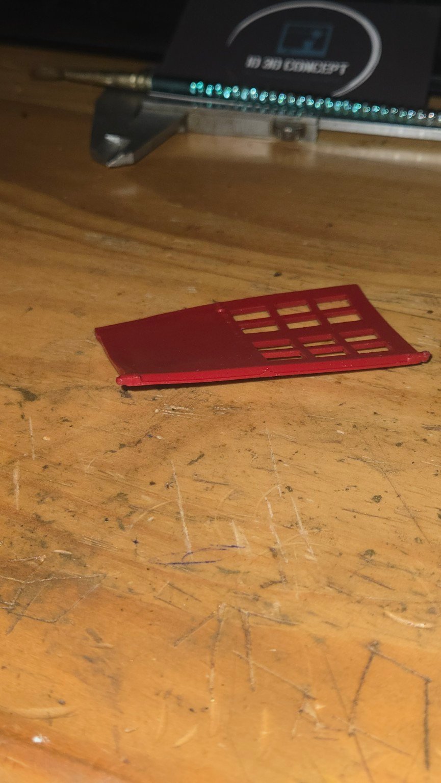 Porte rouge d’origine vue de côté, montrant sa déformation.